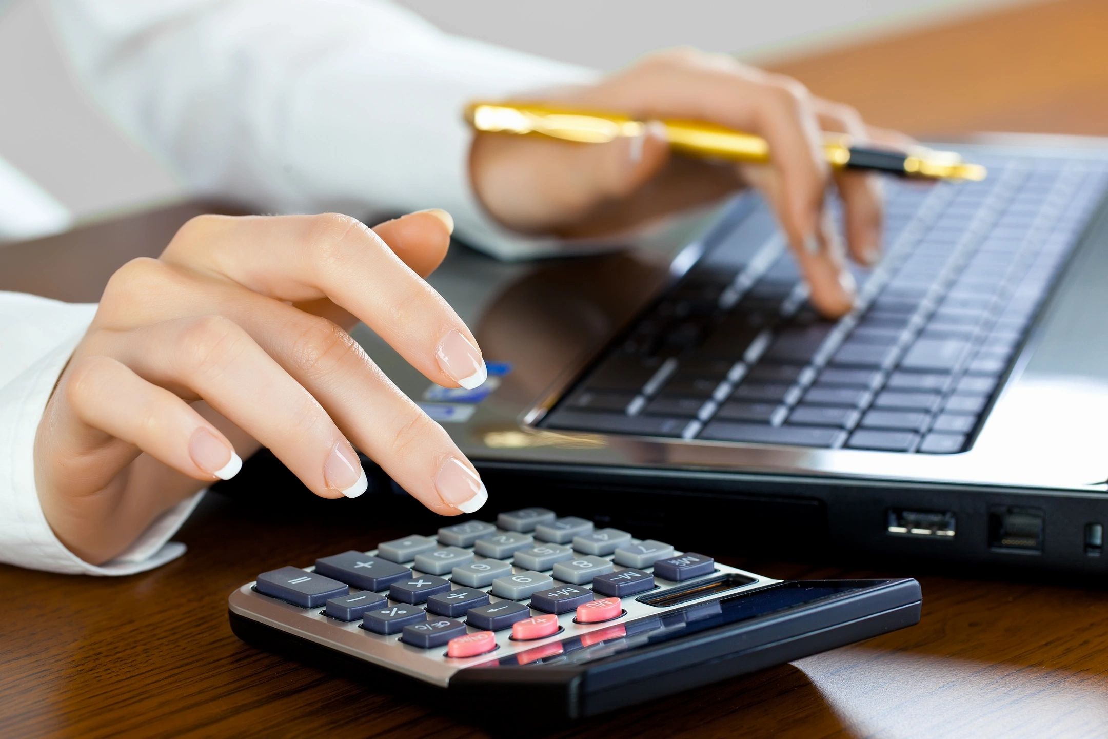 Two people working at a desk with a laptop